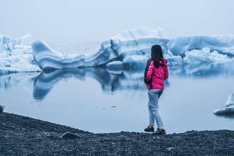 Traveling Alone? These 10 Destinations Are Perfect for Solo Adventures 8 10 Best Destinations for Solo Travel Right Now, Woman in Jökulsárlón Lagoon Iceland - Iceland Glaciers Tour - 9 Day Iceland Itinerary with Kids